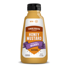 Load image into Gallery viewer, A 12 oz squeeze bottle of True Made Foods GF Keto Honey Mustard on a white background. The bottle contains golden mustard and features a black cap with a white, orange, and purple label.