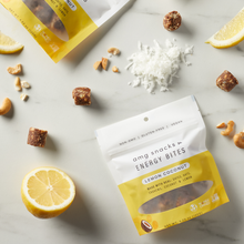 Load image into Gallery viewer, Lemon Coconut Energy Bites on marble with coconuts and lemon slices.