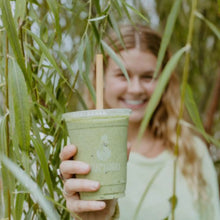 Load image into Gallery viewer, Girl holding a green smoothie through palm trees highlighting the reed straw
