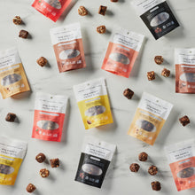 Load image into Gallery viewer, On-the-go packages of AMG Snacks scattered on a marble background.