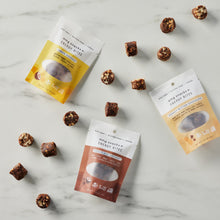 Load image into Gallery viewer, Lemon Coconut, Chocolate Coconut, and Peanut Butter Chocolate Energy Bites scattered on a marble background.