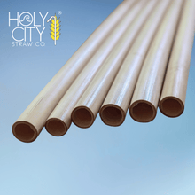 Load image into Gallery viewer, Jumbo reed stem drinking straws by Holy City Straw Co. displayed against a blue backdrop, highlighting their natural hollow texture and sustainable composition