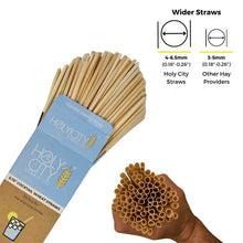 Load image into Gallery viewer, A comparison image showing a pack of Holy City Straw Co. 5.75-inch cocktail wheat straws with a label, illustrating the wider diameter (4-6.5mm) of Holy City straws versus the narrower diameter (3-5mm) of other hay providers. The image also features a hand holding a bundle of straws for visual reference.