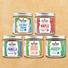 Load image into Gallery viewer, A glass jar of Golden Crystal Turbinado Sugar by Burlap & Barrel, set against a background of raw sugar crystals.