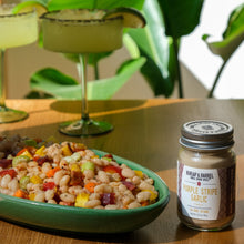 Load image into Gallery viewer, Jar of Burlap &amp; Barrel Purple Stripe Garlic on a table with a dish of salad in the background
