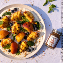 Load image into Gallery viewer, Plate of grilled peaches, blueberries, and mint leaves, accompanied by a jar of Royal Cinnamon from Burlap &amp; Barrel
