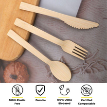 Load image into Gallery viewer, Holy City Straw Co. presents their sustainable bamboo cutlery set against a soft fabric background, with a rolling pin partially visible. The set includes a knife, fork, and spoon, each boasting a natural wood finish. Icons underscore the utensils&#39; eco-friendly qualities: 100% plastic-free, durable, 100% USDA biobased, and certified compostable.
