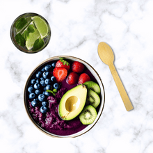 Load image into Gallery viewer, A refreshing acai bowl topped with sliced strawberries, blueberries, kiwi, and half an avocado, served next to an unwrapped bamboo spoon from Holy City Straw Co. A glass of lime-infused water with mint leaves is placed on a marble surface alongside the bowl.
