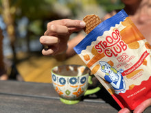 Load image into Gallery viewer, Photo of someone getting a mini stroopwafel out of the bag, next to a coffee cup.
