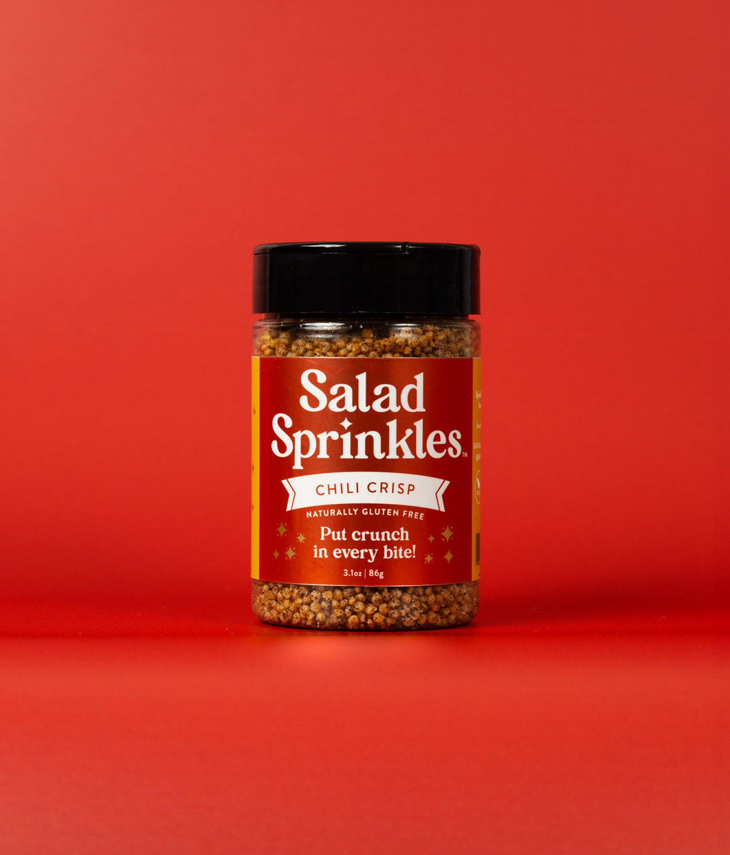 A bottle of Chili Crisp SaladSprinkles on a red background