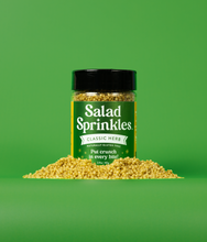 Load image into Gallery viewer, A bottle of Classic Herb SaladSprinkles nestled in a little pile of salad sprinkles on a green background.


