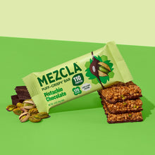 Load image into Gallery viewer, MEZCLA Pistachio Chocolate puff-crispy protein bar package on green background with pistachios and stacked bar pieces showing texture
