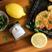 Load image into Gallery viewer, Verano Lemon Pepper sitting next to a chicken cutlet, lemons, and herbs
